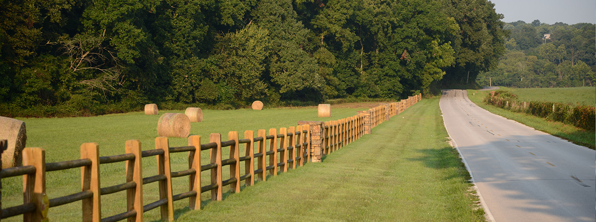 Country road with fence and hay bales. 